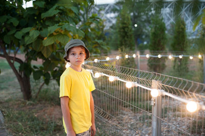 Portrait of boy standing against trees
