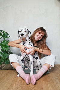 Portrait of woman with dog sitting on floor at home