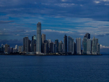 Sea by city buildings against sky