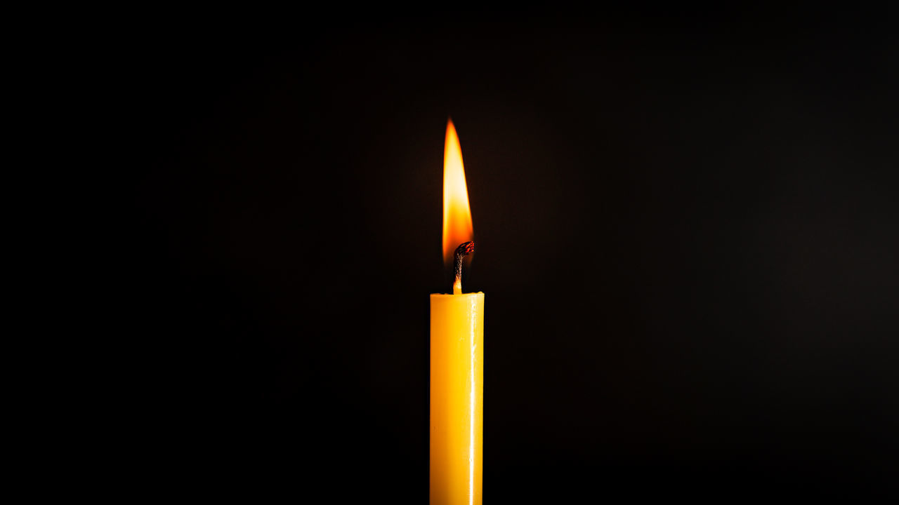 CLOSE-UP OF LIT CANDLE IN DARKROOM