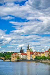 Buildings at waterfront against cloudy sky