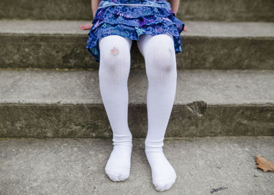 Bottom half of shoeless little girl with ripped tights and dirty knees