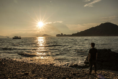 Silhouette of person looking at sea against sky during sunset