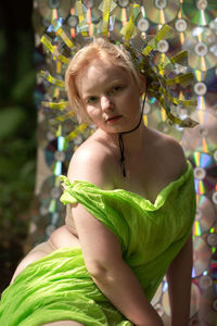 Portrait of young woman sitting against plants