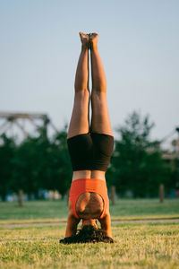 Upside down image of woman exercising on grassy field