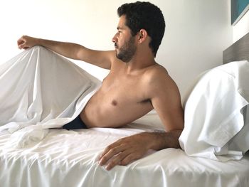 Shirtless man lying on bed