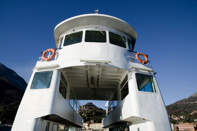 Low angle view of boat moored at harbor against clear blue sky