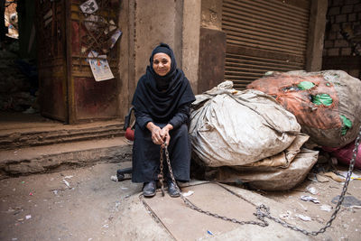 Full length of man sitting on street in city