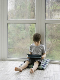 Rear view of boy looking through window