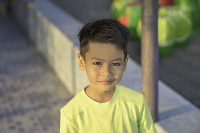 Portrait of boy on footpath in city