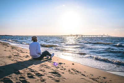 Rear view of woman sitting on beach