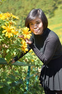 Portrait of girl standing on yellow flowering plants