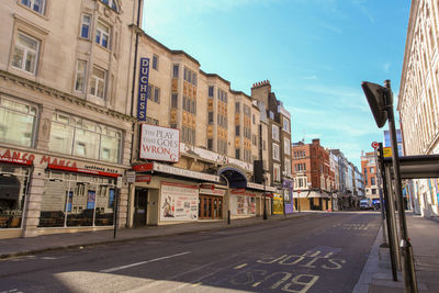 Road by buildings in city against sky