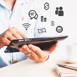 Midsection of man using smart phone on table