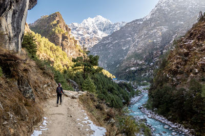 Rear view of woman hiking on mountain road