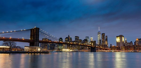 Scenic view of illuminated bridge over calm sea against cloudy sky