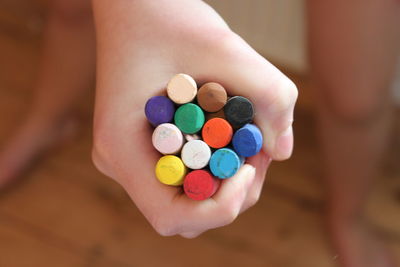 Cropped hand of child holding colorful crayons