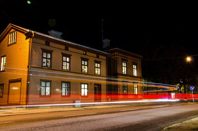 Light trails on street against illuminated buildings at night