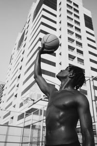 Low angle view of man playing with ball in city