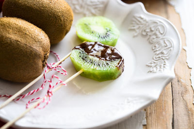 Close-up of kiwi with melted chocolate served on table