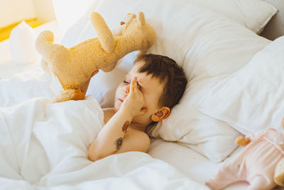 Boy just waking up in bed holding a stuffed toy