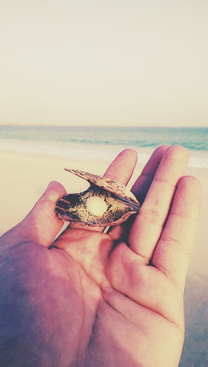 person, holding, part of, sea, cropped, human finger, personal perspective, horizon over water, lifestyles, copy space, leisure activity, beach, water, unrecognizable person, clear sky, close-up