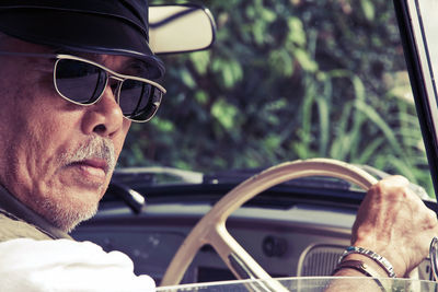 Close-up portrait of man wearing sunglasses in car 