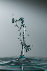 Close-up of drop falling on water against white background