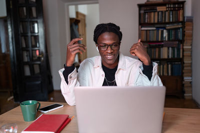 Smiling young african man tutor wearing wireless earbuds talking by webcam teaching online from home