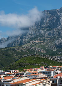 Aerial view of townscape by mountain against sky