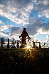 Silhouette man with bicycle on field