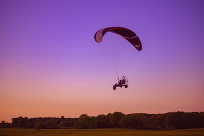 Person paragliding against sky during sunset