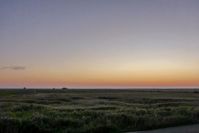 Scenic view of grassy landscape against sky during sunset