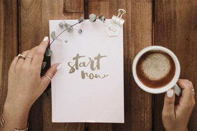 Directly above shot of hand holding coffee cup on table