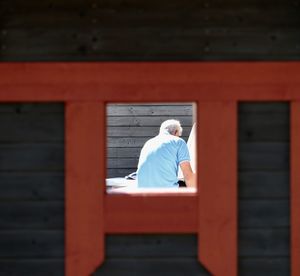 Rear view of man sitting on red structure