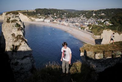 Rear view of man standing on rock by sea