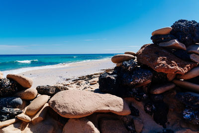 Rocks on beach against blue sky