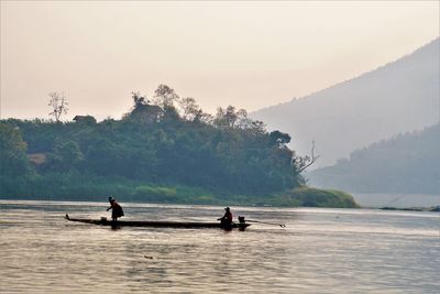 People on boat in river against sky