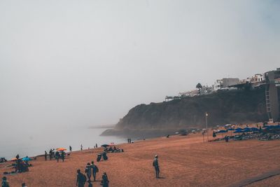 People on beach against clear sky