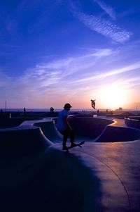 Silhouette man skateboarding at park against sky during sunset