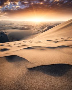 Scenic view of sand dunes against sky during sunset