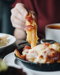 Close-up of woman eating fresh pizza and french fries at restaurant