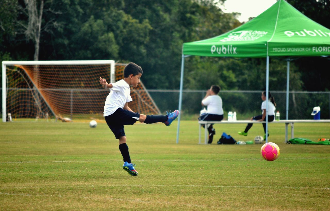 grass, lifestyles, leisure activity, sport, men, full length, green color, playing, field, boys, casual clothing, togetherness, childhood, playground, soccer, skill, person, competition