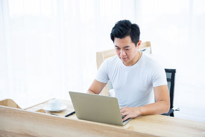 Young man using mobile phone while sitting on table