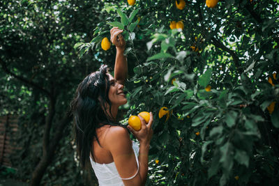 Young woman with orange fruits on tree