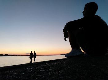 Rear view of silhouette man and woman standing on beach