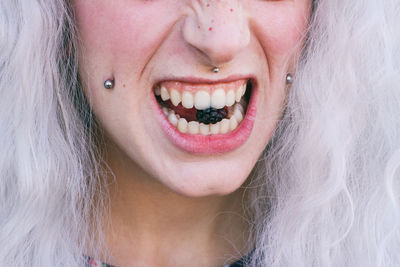 Cropped image of female model eating blackberry