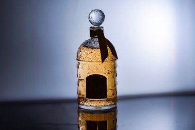 Close-up of glass bottle on table against wall
