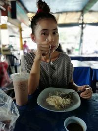 Portrait of young woman sitting at restaurant table