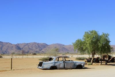 Car in desert against clear blue sky